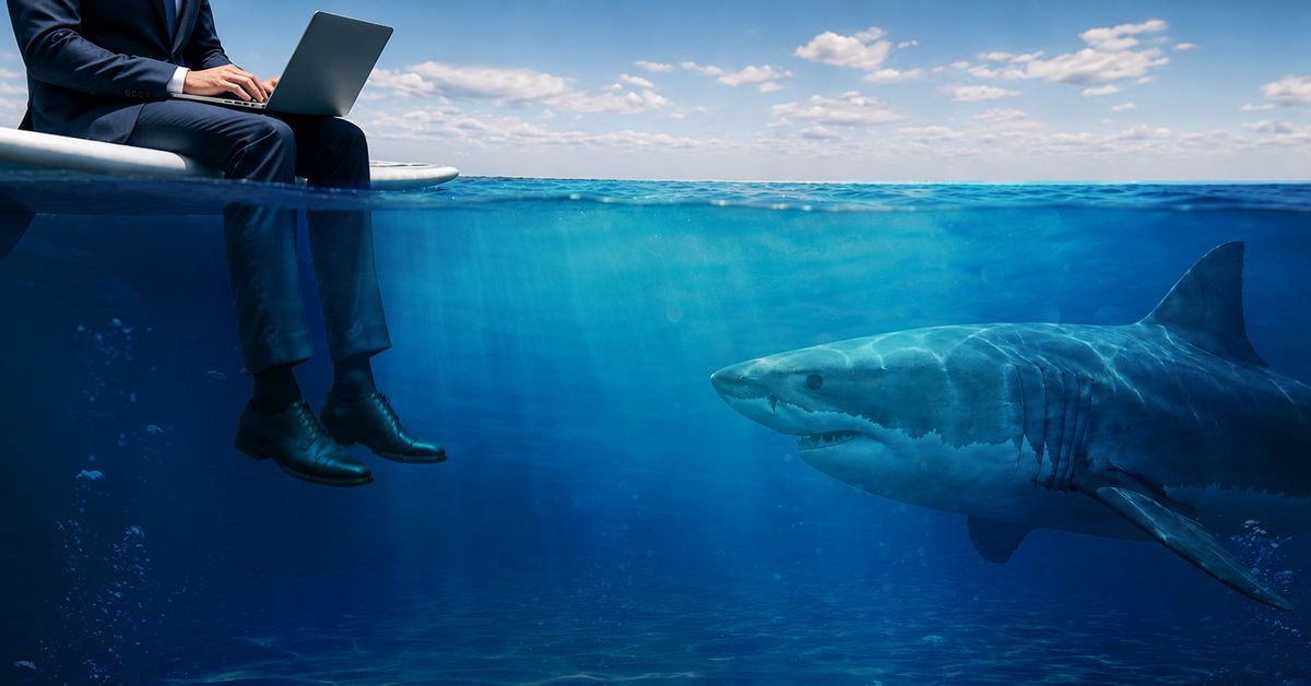 A businessman works on his laptop above the waterline while a great white shark circles unnoticed below, illustrating the summer cybersecurity threats hiding beneath everyday business activity.